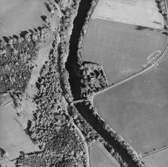 Oblique aerial view centred on the remains of the tower-house with road bridge adjacent, taken from the WNW.