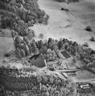 Oblique aerial view centred on the country house with farmsteading adjacent, taken from the NNW.