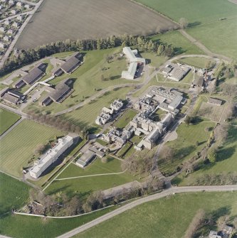 Oblique aerial view centred on the hospital and chapel, taken from the SW.