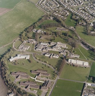 Oblique aerial view centred on the hospital and chapel, taken from the NW.