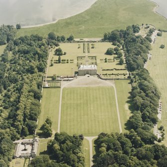Oblique aerial view of Kinross House centred on the country house with garden, stables and a church and burial ground in the background, taken from the NW.
