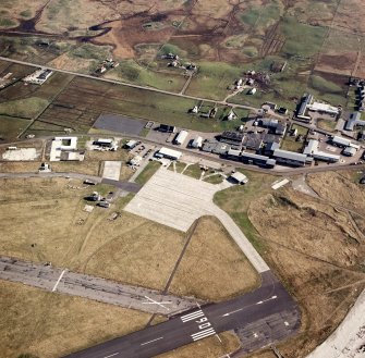 Oblique aerial view centred on the village with the airfield adjacent, taken from the N.