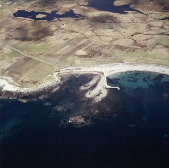 Oblique aerial view centred on the jetty, with the remains of the dun adjacent, taken from the SW.