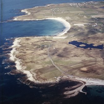 General oblique aerial view looking across the jetty towards the township of Balvanich and the crofting township of Aird, with the remains of the dun adjacent, taken from the SSW.