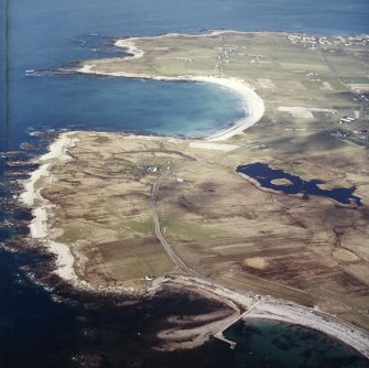 General oblique aerial view looking across the jetty towards the township of Balvanich and the crofting township of Aird, with the remains of the dun adjacent, taken from the SSW.