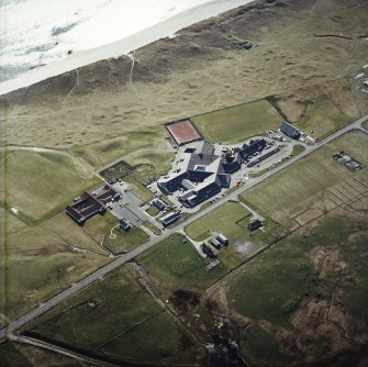 Oblique aerial view centred on the school, the museum and the hotel, with the site of the smithy adjacent, taken from the NE.