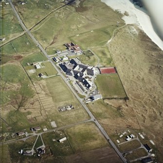 Oblique aerial view centred on the school, the museum and the hotel, with the site of the smithy adjacent, taken from the NNW.