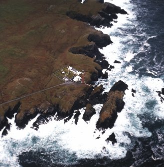Oblique aerial view centred on the lighthouse with the remains of the enclosures adjacent, taken from the ENE.