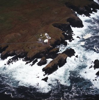 Oblique aerial view centred on the lighthouse with the remains of the enclosures adjacent, taken from the NE.