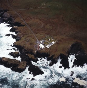 Oblique aerial view centred on the lighthouse with the remains of the enclosure adjacent, taken from the NNW.