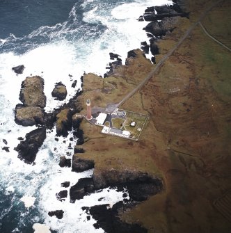 Oblique aerial view centred on the lighthouse with the remains of the enclosure adjacent, taken from the W.
