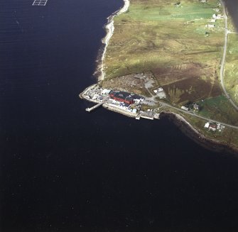 Oblique aerial view centred on the factory and laboratory with the pier and remains of lazy beds adjacent, taken from the SE.