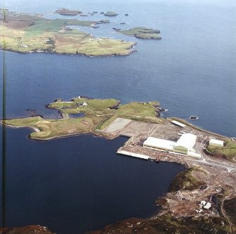 Oblique aerial view centred on the oil rig construction yard with the lighthouse and the remains of the coast battery adjacent, taken from the W.