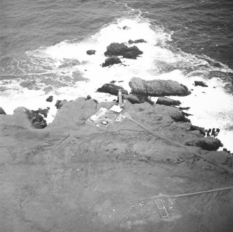Oblique aerial view centred on the lighthouse with the remains of the enclosure adjacent, taken from the S.