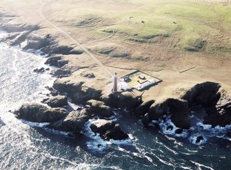 Oblique aerial view centred on the lighthouse with the enclosure and lazy beds adjacent, taken from the NNW.