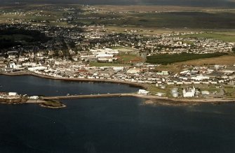 Oblique aerial view centred on the breakwater with the power station and town adjacent, taken from the S.