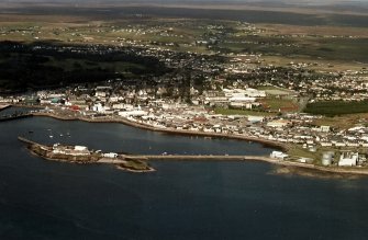 Oblique aerial view centred on the breakwater with the power station and town adjacent, taken from the S.