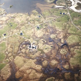Oblique aerial view centred on the township and remains of the blackhouses, with the remains of the cairn and the broch adjacent, taken from the ENE.