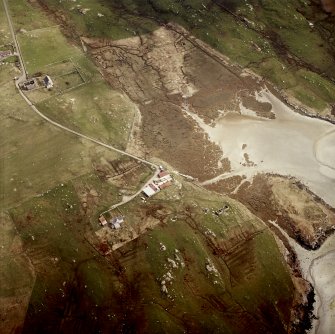 Oblique aerial view centred on the cottage with the manse and the remains of the church adjacent, taken from the NW.