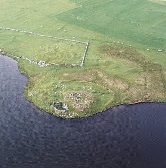 Oblique aerial view centred on the remains of the broch with the remains of the buildings and burnt mound adjacent, taken from the S.