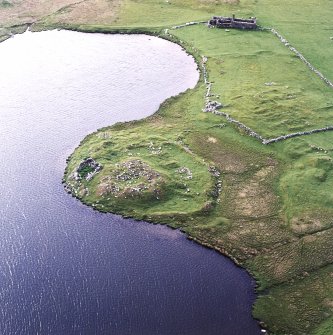 Oblique aerial view centred on the remains of the broch with the remains of the buildings, burnt mound and croft buildings adjacent, taken from the ESE.