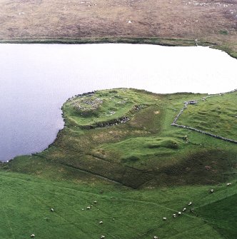 Oblique aerial view centred on the remains of the broch with the remains of the buildings and burnt mound adjacent, taken from the E.