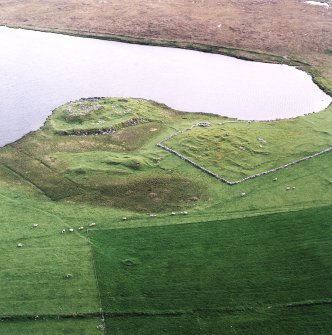 Oblique aerial view centred on the remains of the broch with the remains of the buildings and burnt mound adjacent, taken from the ENE.