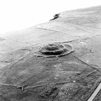 Oblique aerial view centred on the remains of the broch and field-system, taken from the ENE.