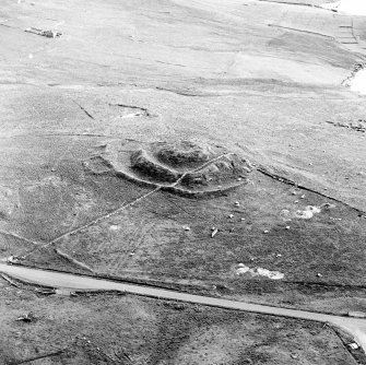 Oblique aerial view centred on the remains of the broch and field-system, taken from the NNE.