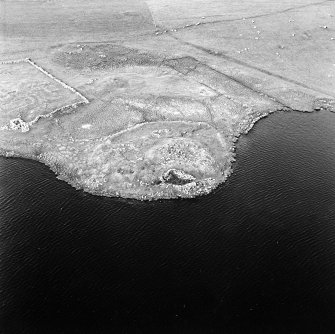 Oblique aerial view centred on the remains of the broch with the remains of the buildings and burnt mound adjacent, taken from the SW.