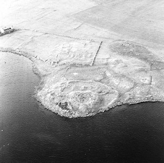 Oblique aerial view centred on the remains of the broch with the remains of the buildings, burnt mound and croft buildings adjacent, taken from the SSE.