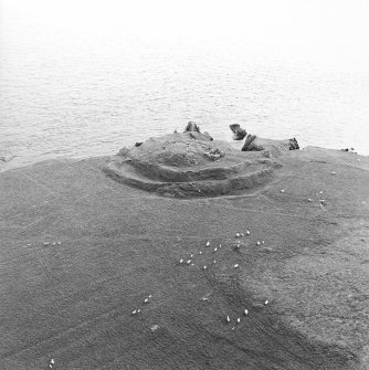 Oblique aerial view centred on the remains of the broch, taken from the NNE.
