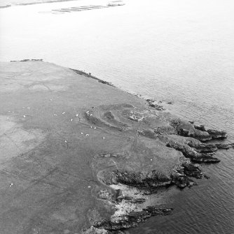 Oblique aerial view centred on the remains of the broch, taken from the NNW.