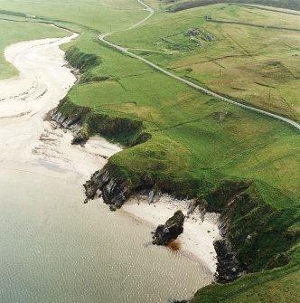 Oblique aerial view centred on the remains of the broch with the remains of the farmstead adjacent, taken from the NE.