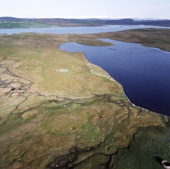 Oblique aerial view of the remains of the enclosure, stock enclosure, settlement and field-system, taken from the NW.