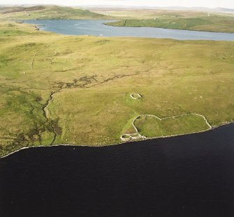 Oblique aerial view of the remains of the enclosure, stock enclosure, settlement and field-system, taken from the SW.