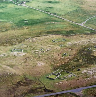 Oblique aerial view centred on the remains of the building, planticrubs, enclosures and quarries, taken from the NNE.