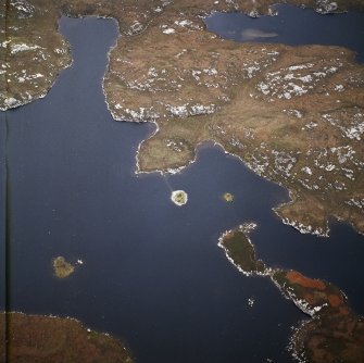 Oblique aerial view centred on the remains of the broch with the causeway adjacent, taken from the SW.