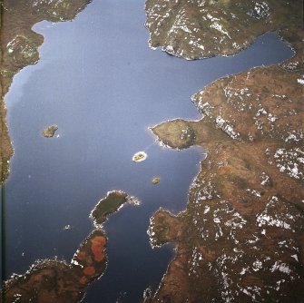 Oblique aerial view centred on the remains of the broch with the causeway adjacent, taken from the SE.