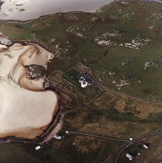 Oblique aerial view centred on the remains of the burial ground with the old manse, walled garden and lazy beds adjacent, taken from the E.