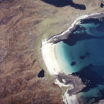 Oblique aerial view centred on the remains of the shieling huts and lazy-beds with the remains of the fish trap adjacent, taken from the ESE.

