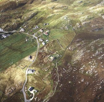 Oblique aerial view centred on the remains of the broch with the remains of the blackhouse and township adjacent, taken from the ESE.