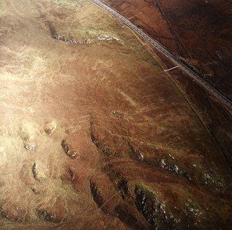 Oblique aerial view centred on the remains of the stone circle, taken from the WSW.