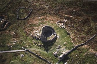 Oblique aerial view centred on the remains of the broch, taken from the NNE.