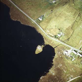 Oblique aerial view centred on remains of the broch with the possible crannog adjacent, taken from the SE.