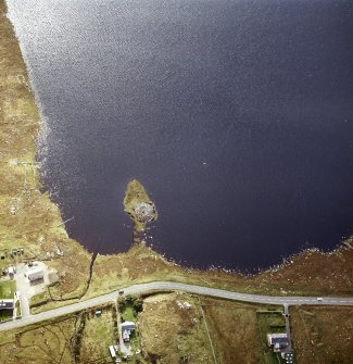 Oblique aerial view centred on remains of the broch with the possible crannog adjacent, taken from the N.