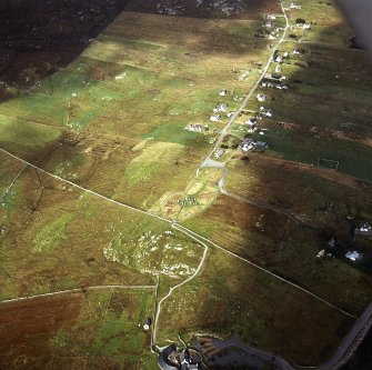 Oblique aerial view centred on the remains of the stone circle and stone alignments with the township and lazy beds adjacent, taken from the SSE.