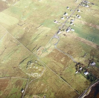Oblique aerial view centred on the remains of the stone circle, chambered cairn and stone alignments with the township and lazy beds adjacent, taken from the SSE.