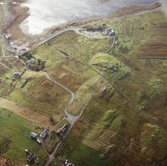 Oblique aerial view centred on the remains of the stone circle, chambered cairn and stone alignments with the township and lazy beds adjacent, taken from the NNW.
