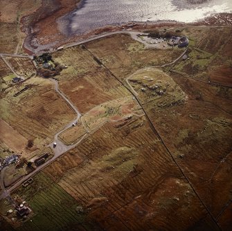 Oblique aerial view centred on the remains of the stone circle, chambered cairn and stone alignments with the township and lazy beds adjacent, taken from the NW.